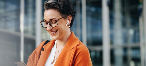 Smiling businesswoman reading a text message on her phone while commuting to her office in the city