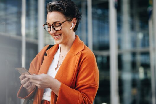 Smiling businesswoman reading a text message on her phone while commuting to her office in the city