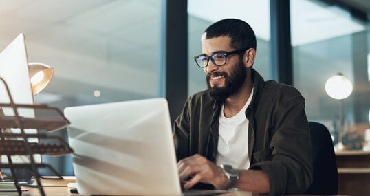 Smile, work and a businessman with a laptop for an email, communication or online coding. Happy, programming and a male programmer typing on a computer for web or software development in an office