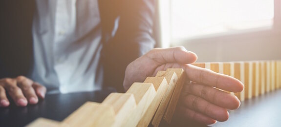 Problem Solving,Close up view on hand of business woman stopping falling blocks on table for concept about taking responsibility.