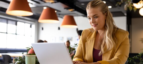 Happy caucasian casual businesswoman using laptop at desk