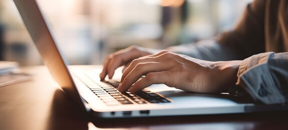 Close up of a business man working on a laptop, typing with his hands for work in office environment home office