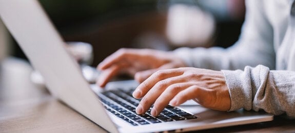 Close up of hands typing on a laptop.