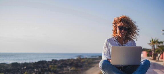 Happy lifestyle digital nomad young cheerful woman work outdoor with laptop computer - people and modern technology job and communication related - alternative office at the beach