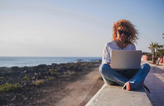 Happy lifestyle digital nomad young cheerful woman work outdoor with laptop computer - people and modern technology job and communication related - alternative office at the beach