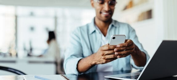 Business man sitting in an office and using a smartphone