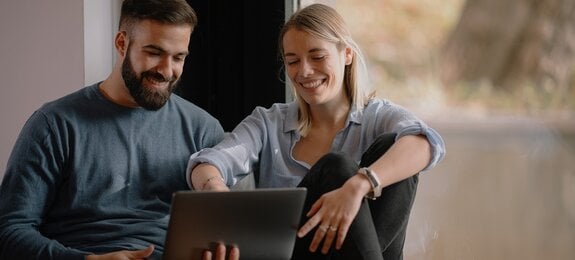 Young happy couple. Boyfriend and girlfriend using laptop together.