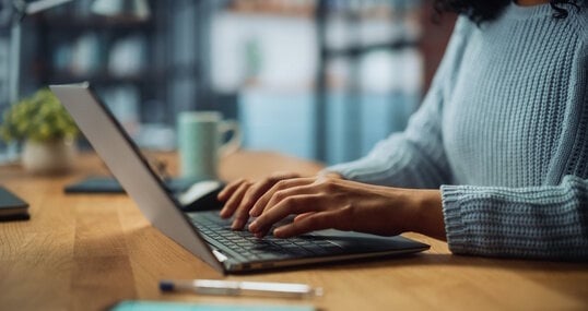 Close Up on Hands of a Female Specialist Working on Laptop Computer at Cozy Home Living Room while Sitting at a Table. Freelancer Woman Chatting Over the Internet on Social Networks.