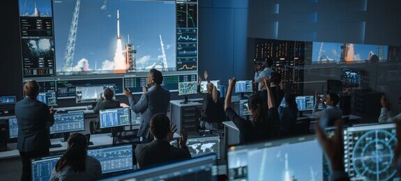 Group of People in Mission Control Center Witness Successful Space Rocket Launch. Flight Control Employees Sit in Front Computer Displays and Monitor the Crewed Mission.