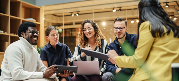 Multiethnic Group of People Meeting and Discussing Innovative Ideas in a Casual Conference Room in the Office. Smiling Colleagues Putting Together a Presentation