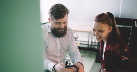 Work partners sitting in office surfing phone in company