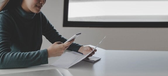 panoramic banner. young woman using mobile smart phone for scan and payment online with family budget cost bills on desk in home office, plan money cost saving, investment, finance, expenses concept