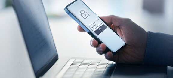 Man holding smart phone with data security on display at office