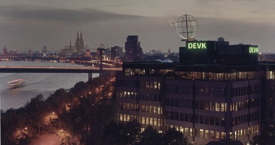 Foto der Firmenzentrale der DEVK mit Kölner Skyline im Hintergrund im Abendlicht