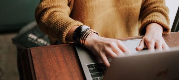 Frau im Pullover arbeitet am Laptop