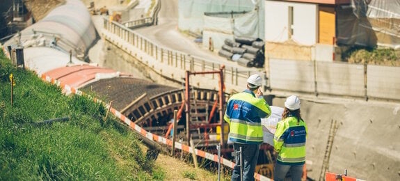 Zwei Bauarbeiter begutachten eine Baustelle