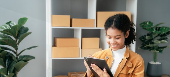 Junge Frau sitzt am Schreibtisch und arbeitet am Tablet